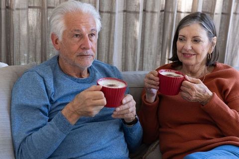 Senior couple relaxing on sofa with warm beverages