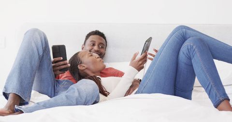 Couple Relaxing on Bed with Smartphones in Sunny Bedroom