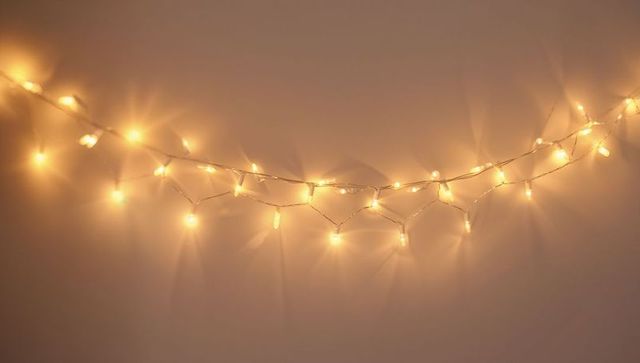 Warm led string lights casting soft halo glow on blank wall for cozy backdrop and bokeh