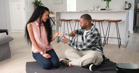 Couple Celebrating at Home with Champagne on Cozy Floor Setting
