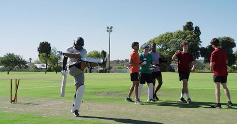 Indian wicketkeeper appealing after breaking bails as teammates celebrate on cricket pitch