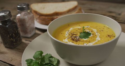 Warm Carrot Soup with Crusty Bread on Rustic Table