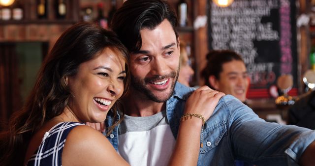 Young couple taking a selfie together in a stylish cafe while smiling. Ideal for promoting social interactions, lifestyle blogs, cafe marketing, or relationship advice campaigns.