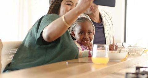 African american family taking selfie during cozy breakfast at sunlit kitchen counter
