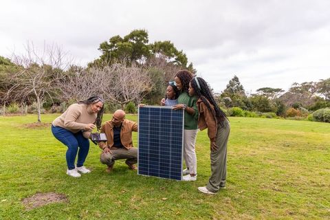 Multigenerational african american family examining solar panel and tablet outdoors