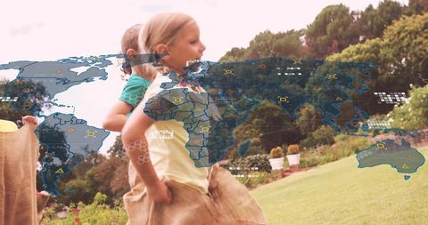 Children playing sack race in garden with global map overlay representing teamwork and fun