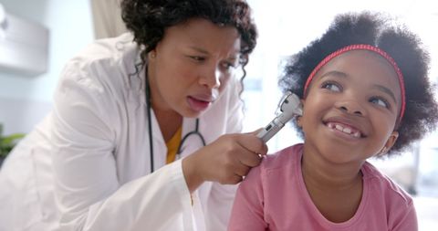 Doctor Examining Smiling Child with Otoscope