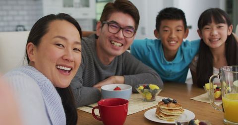 Asian Family Enjoying Breakfast Smiling Around Table - Download Free Stock Images Pikwizard.com