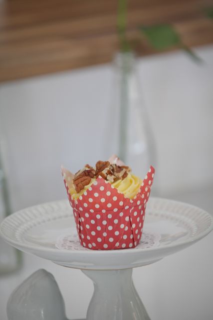This delicious cupcake with a red polka dot wrapper sits beautifully on a white plate. Ideal for illustrations of delicious treats, bakery promotions, dessert menus, or food blogs. Perfect for adding a touch of sweetness to invitations, ads, and social media posts.
