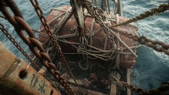 Sailors tightening ropes on deck of weathered fishing vessel with canvas-wrapped fender