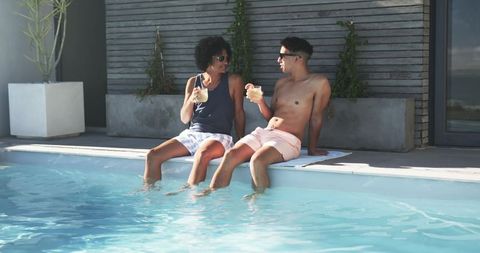 Relaxing poolside with cocktails, two men soaking feet and chatting on private deck