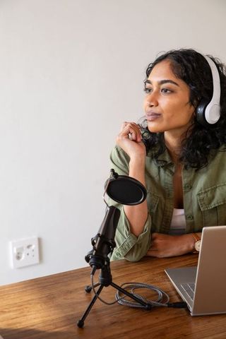 Podcaster at work: woman with headphones and microphone at desk