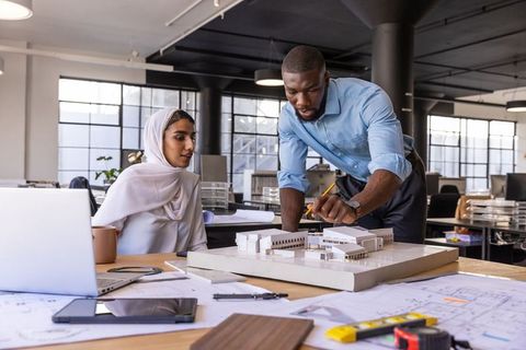 Diverse coworkers collaborating over architectural project model in office