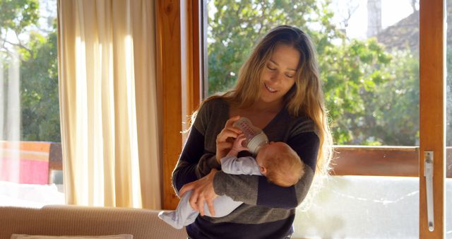 Young Mother Feeding Baby with Bottle in Sunlit Room - Download Free Stock Images Pikwizard.com