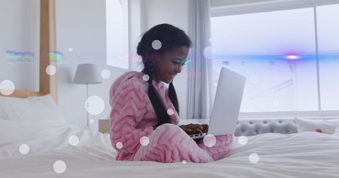 Young girl in pajamas using laptop with digital effects