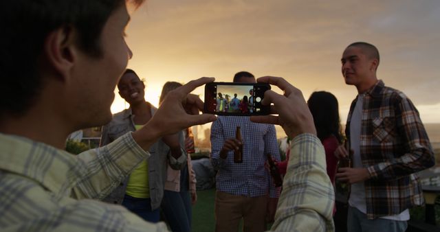 Hands of diverse man taking picture of male and female colleagues drinking beer on sunny rooftop - Download Free Stock Photos Pikwizard.com