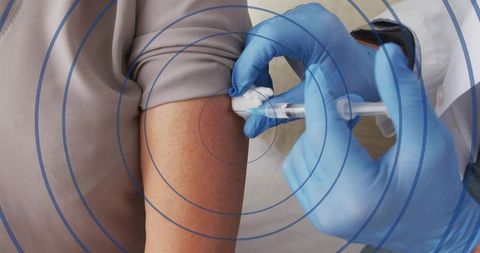 Senior receiving intramuscular vaccine from clinician wearing blue gloves, syringe in arm