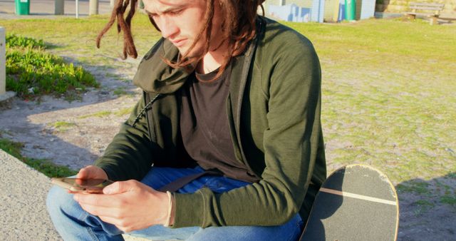 Young Man with Dreadlocks Using Smartphone Relaxing in Park - Download Free Stock Images Pikwizard.com