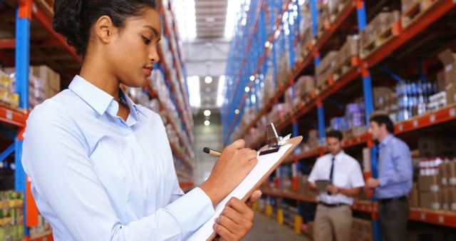 Warehouse Supervisor Checking Inventory with Colleagues in Background - Download Free Stock Images Pikwizard.com