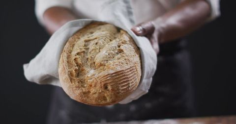 Freshly Baked Artisan Loaf Held by Chef in Apron