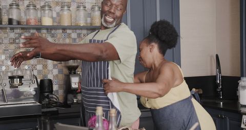 Elderly Couple Playing Together in Kitchen with Joyful Spirit