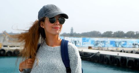 Young woman exploring sunny harbor in casual style