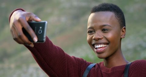 Young Woman Taking Selfie Outdoors with Smiling Expression