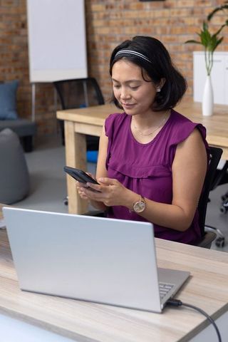 Asian Female Professional Typing on Smartphone in Modern Office
