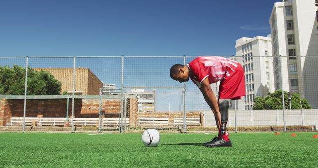 Disabled biracial male football player training on outdoor pitch. Football, sports, fitness, disability and inclusivity.