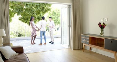 Couple and real estate agent socializing on bright patio