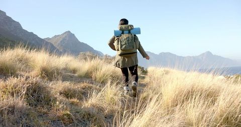 Woman adventuring through grassland with camping gear