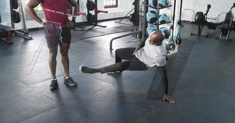 Trainer guiding client performing single-leg strength move with digital fitness data overlay