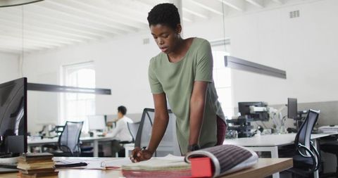 Focused Businesswoman Standing at Desk Making Notes in Office