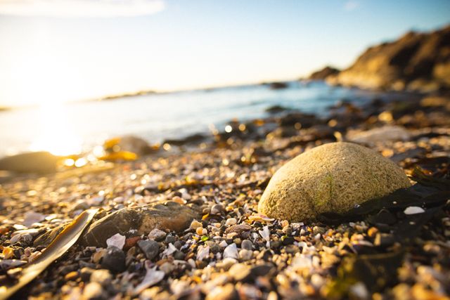 Close-up of small rocks and pebbles on shore at beach during sunset. unaltered, nature, coastline, tranquility.