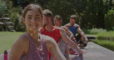 Smiling woman practicing yoga outdoors near pond