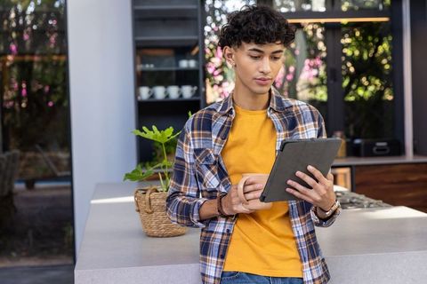 Young Man with Tablet and Coffee Mug Relaxing in Modern Kitchen