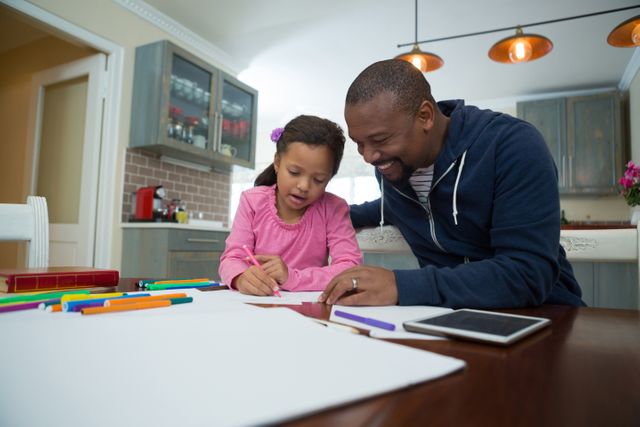 Father assisting his daughter with her school homework at the kitchen table. The girl appears to be focusing on her work while the father provides guidance. Suitable for themes related to education, parenting, family bonding, and home life.