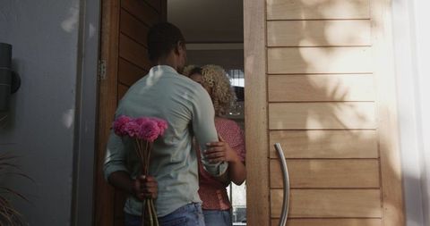Friends Greeting at Doorway With Hidden Flowers