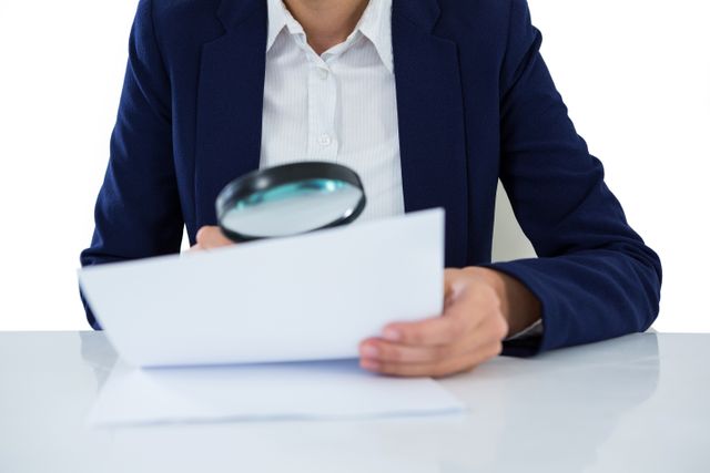 Businesswoman in formal attire closely examining a document with a magnifying glass. Ideal for use in articles or presentations about attention to detail, document verification, business analysis, or corporate diligence.