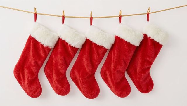 Hanging five red christmas stockings with white fur cuffs on gold rope for festive decor