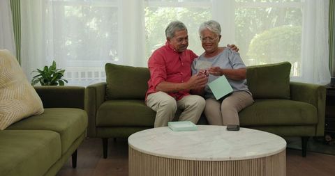 Happy Senior Couple Discovering Ultrasound Picture on Sofa