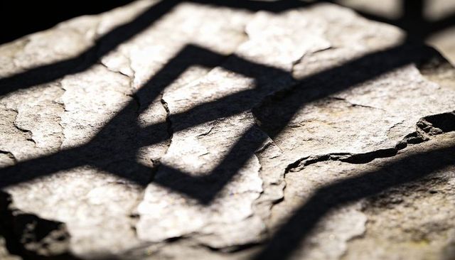 Casting geometric railing shadows over sunlit cracked stone slab highlighting fissures