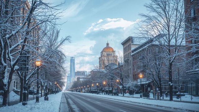 Snow-covered avenue leading to golden domed civic landmark with glowing lamps