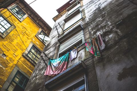 Drying laundry on clothesline between weathered apartment buildings with yellow stucco