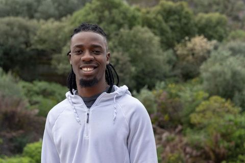 African american man smiling in park wearing light gray hoodie casual outdoor lifestyle