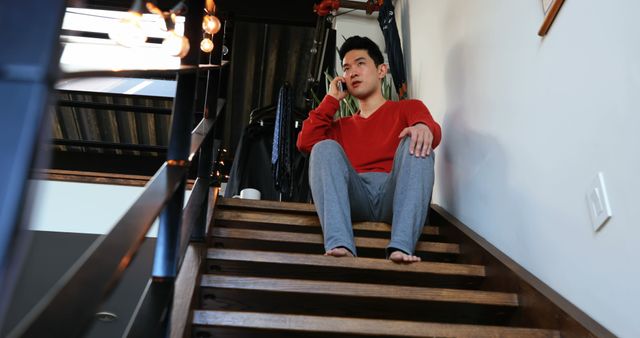 Young Man Sitting on Stairs Talking on Phone at Home - Download Free Stock Images Pikwizard.com