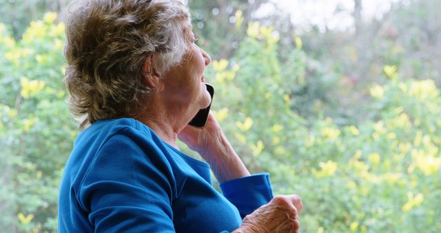 Senior Woman Talking on Phone by Window with Greenery View - Download Free Stock Images Pikwizard.com