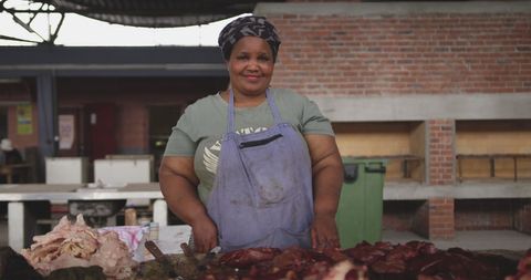 Female butcher in market with display of fresh meat
