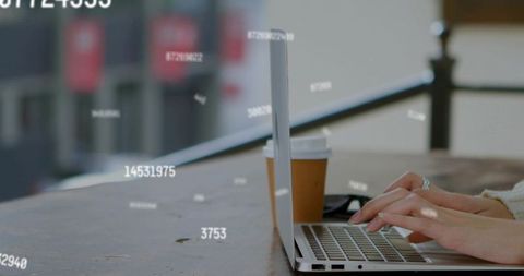 Freelance woman typing on laptop with coffee on urban terrace and floating data overlays