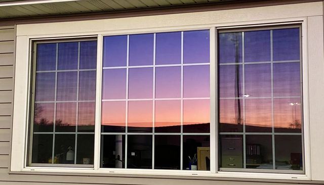 Sunset reflecting in three-panel window grids with office desk silhouette and gradient sky